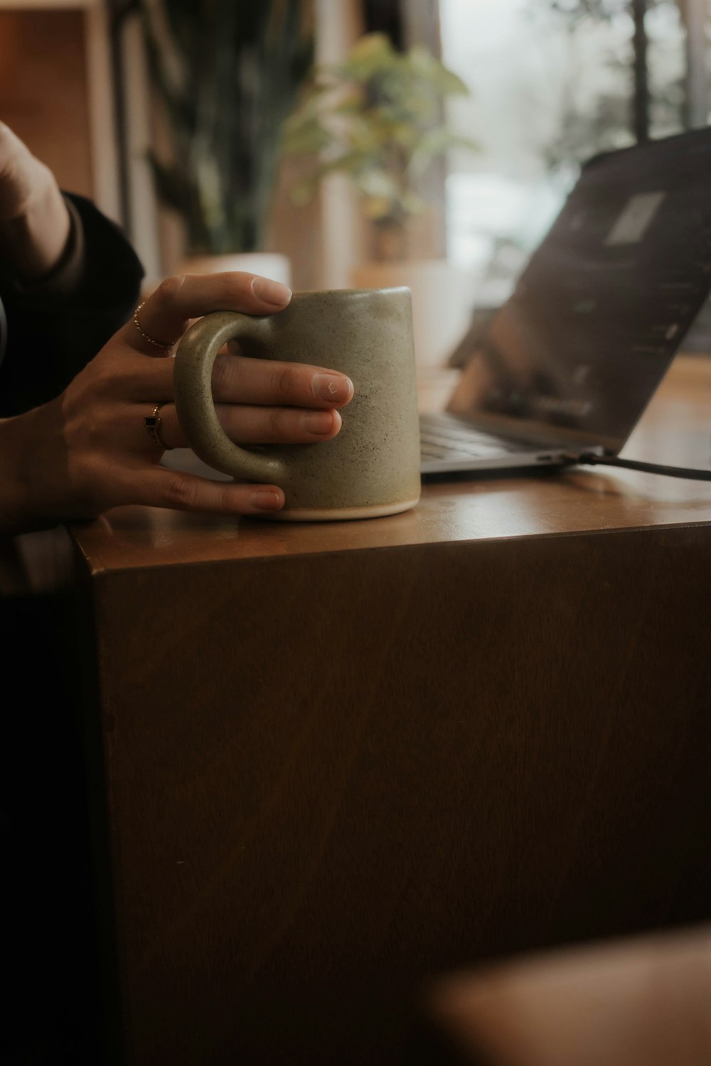 a woman holding a coffee mug in front of a laptop