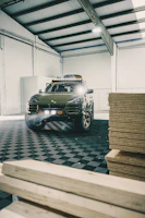 A sleek black SUV with highlighted suspension parts in a workshop.