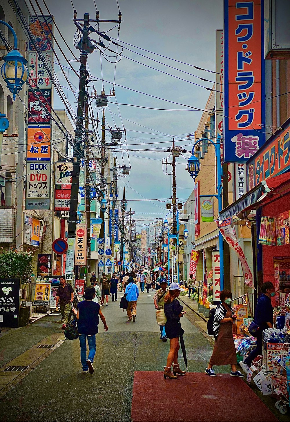 a group of people walking down a street next to tall buildings