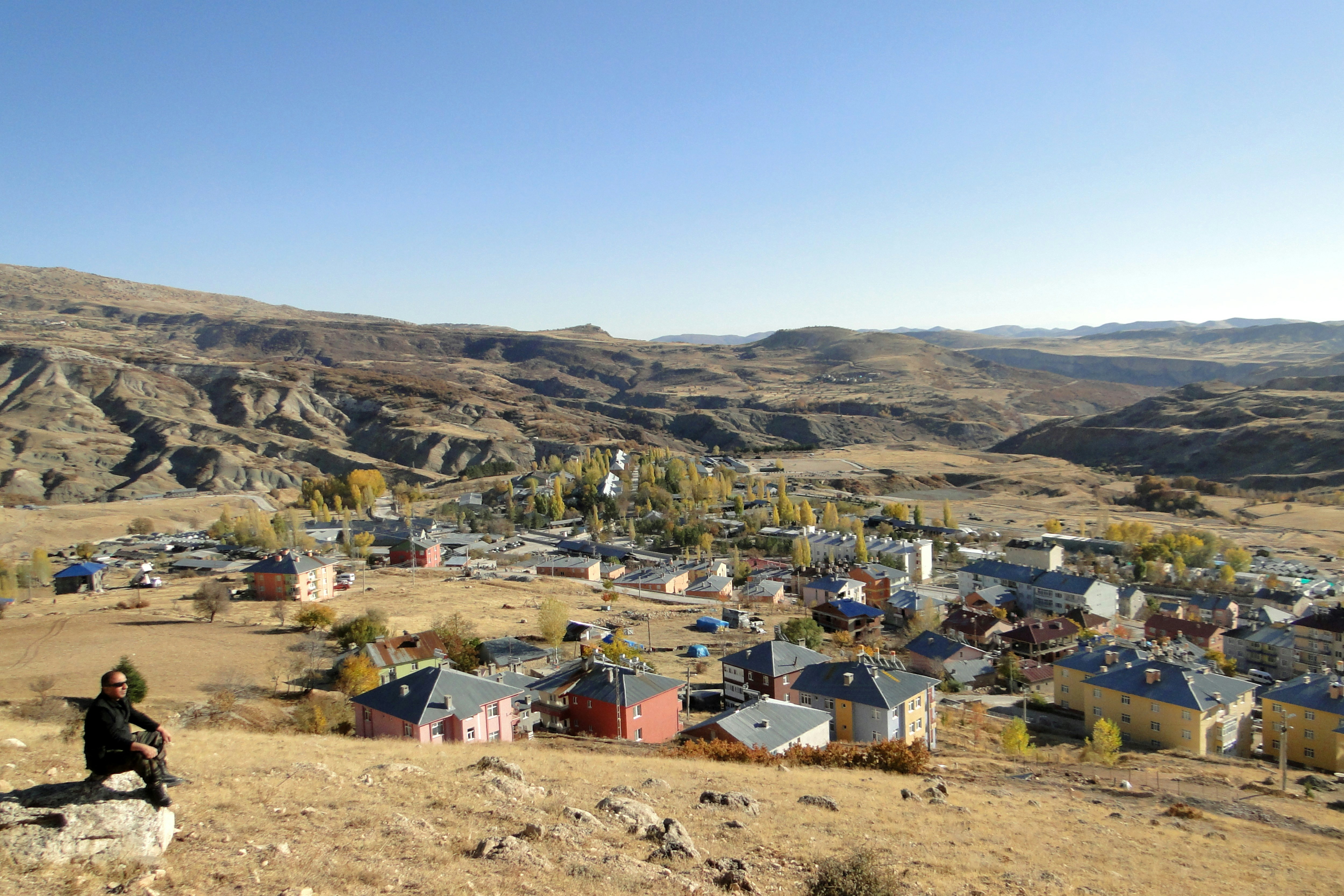 a person sitting on a rock overlooking a town