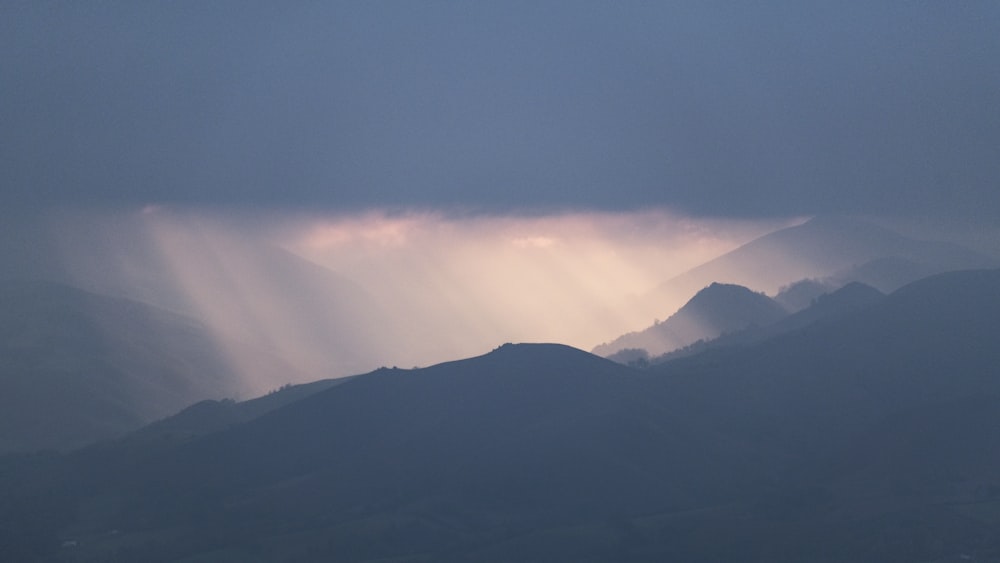 the sun shines through the clouds over the mountains