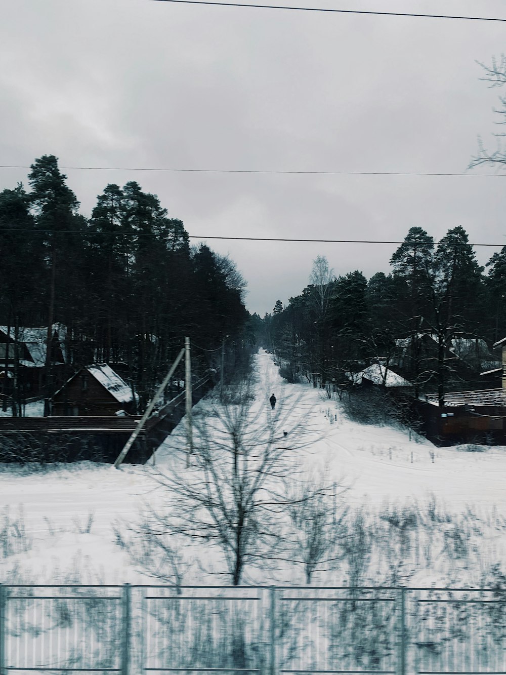 a snow covered road with houses and trees in the background