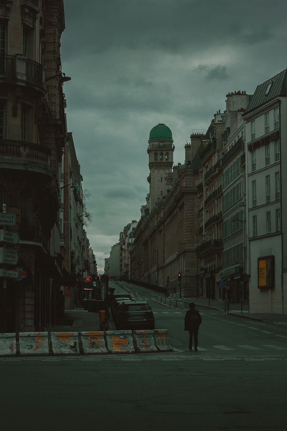 a man walking down a street next to tall buildings