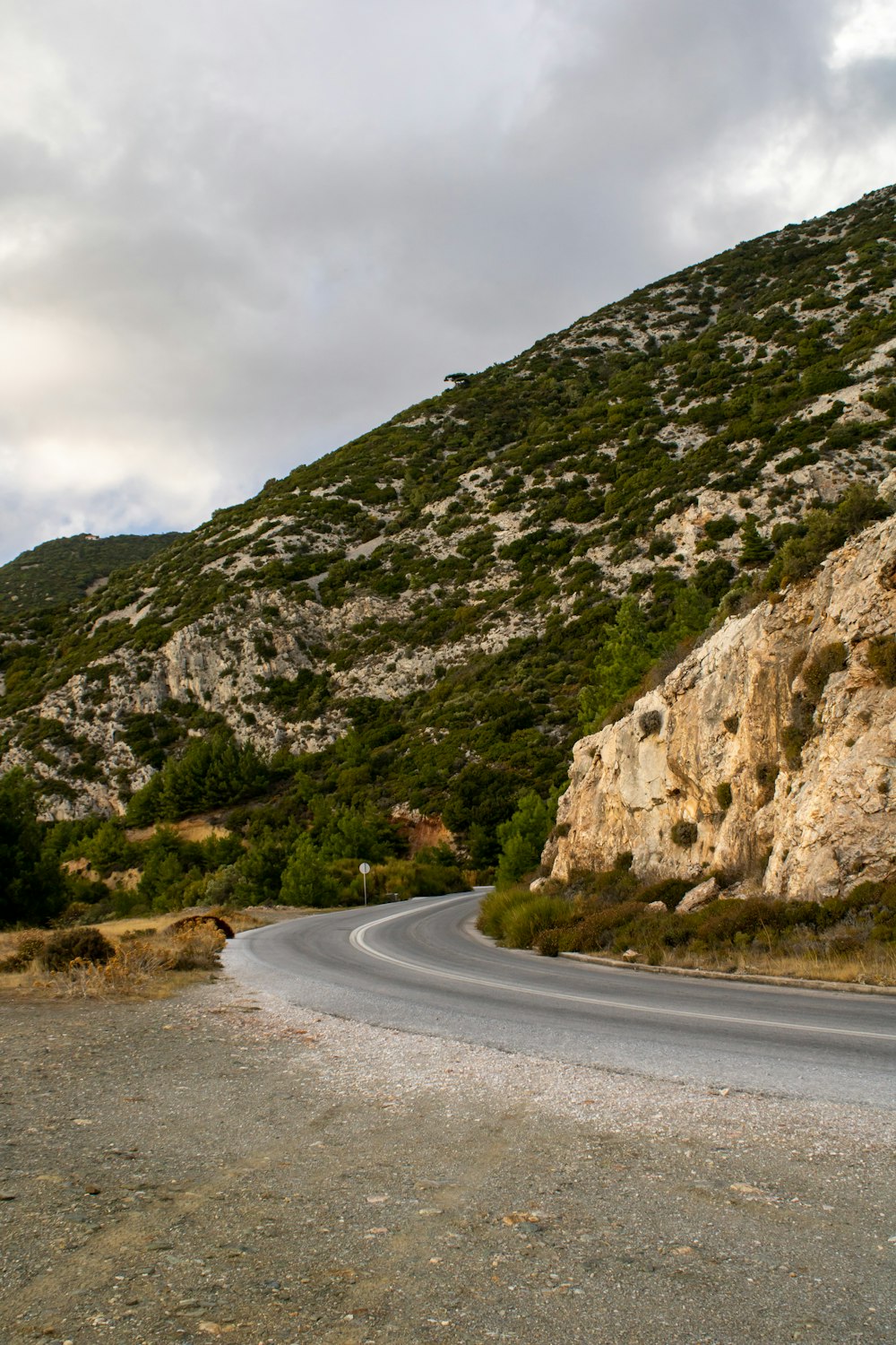 a curve in the road in front of a mountain