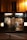 Exterior view of a Moroccan restaurant named Bab Salam with warm lighting illuminating the entrance. The glass facade features decorative designs, offering a glimpse into a cozy interior where patrons sit at tables covered with white tablecloths. Traditional Moroccan lamps hang from the ceiling, enhancing the inviting atmosphere.