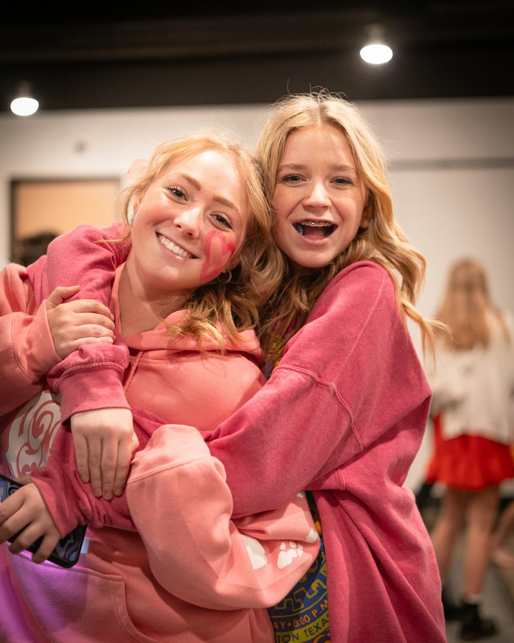 two young women hugging each other in a room