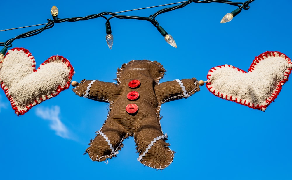 a gingerbread man hanging from a wire with two hearts attached to it
