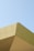 Angular architecture featuring clean lines and sharp edges with a minimalistic style against a clear blue sky. The building appears to have a modern design with sections in varying shades of beige and light green.