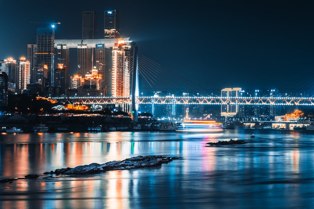 a city skyline at night with a bridge in the background