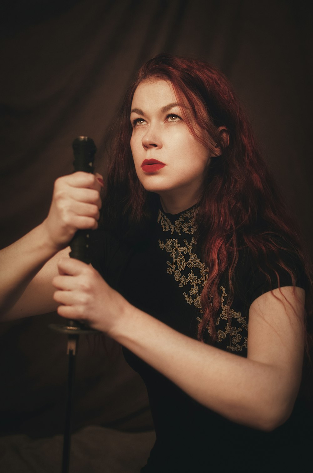 a woman with red hair holding a black umbrella
