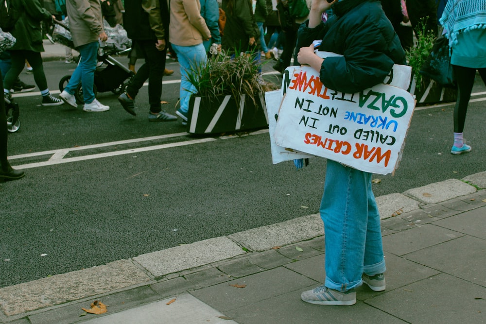 a person standing on a sidewalk holding a sign