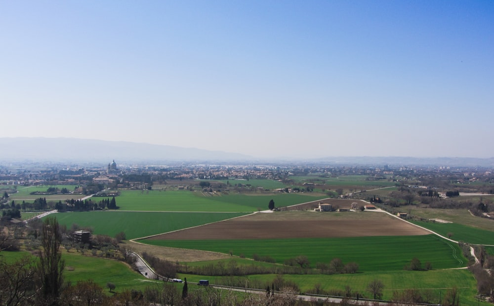 uma vista de um grande campo verde com uma pequena cidade ao longe