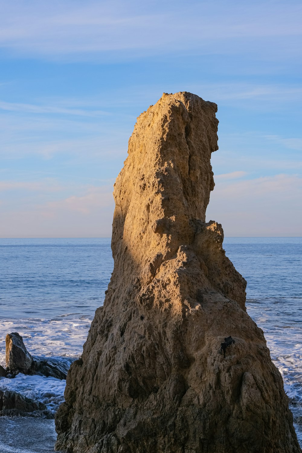 una grande roccia seduta in cima a una spiaggia vicino all'oceano