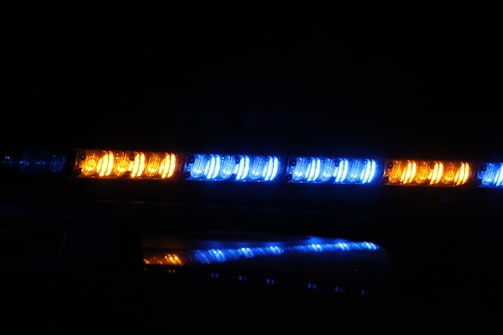 A series of bright, flashing LED lights in blue and amber are positioned in a dark environment, likely indicating an emergency or service vehicle such as a police car or ambulance.