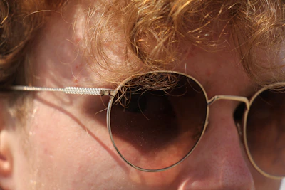 A close-up of a person wearing sleek, modern sunglasses outdoors on a sunny day.