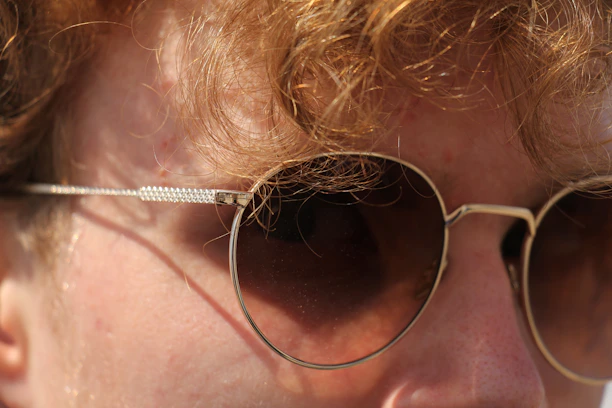 A close-up of a person wearing trendy sunglasses, basking in warm sunlight.
