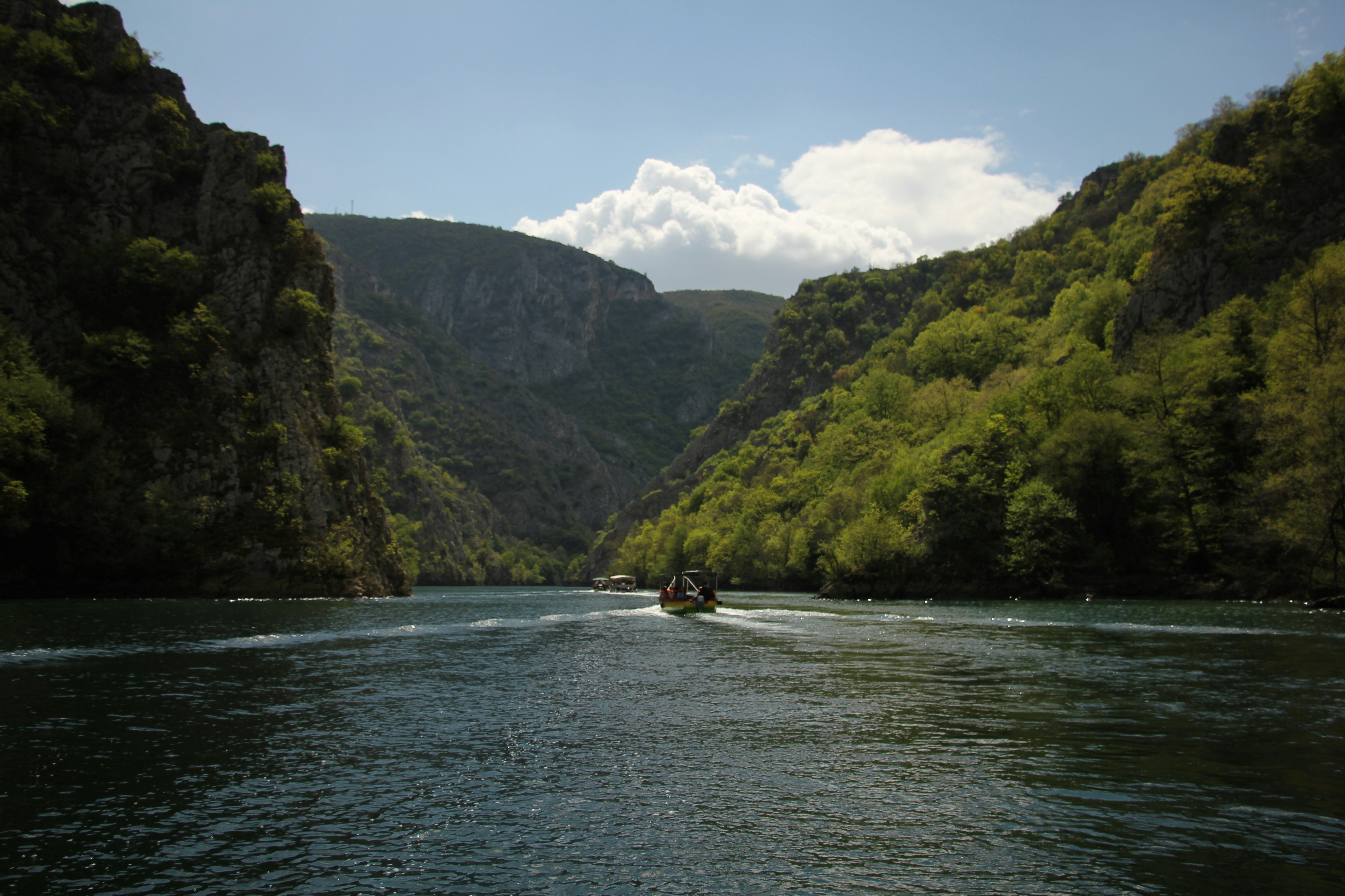 a boat traveling down a river surrounded by mountains