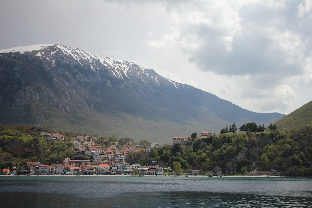 a view of a town on the shore of a lake with mountains in the background