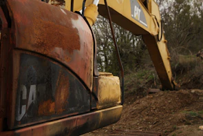 Close-up of a burned excavator with melted metal parts showing heavy damage.