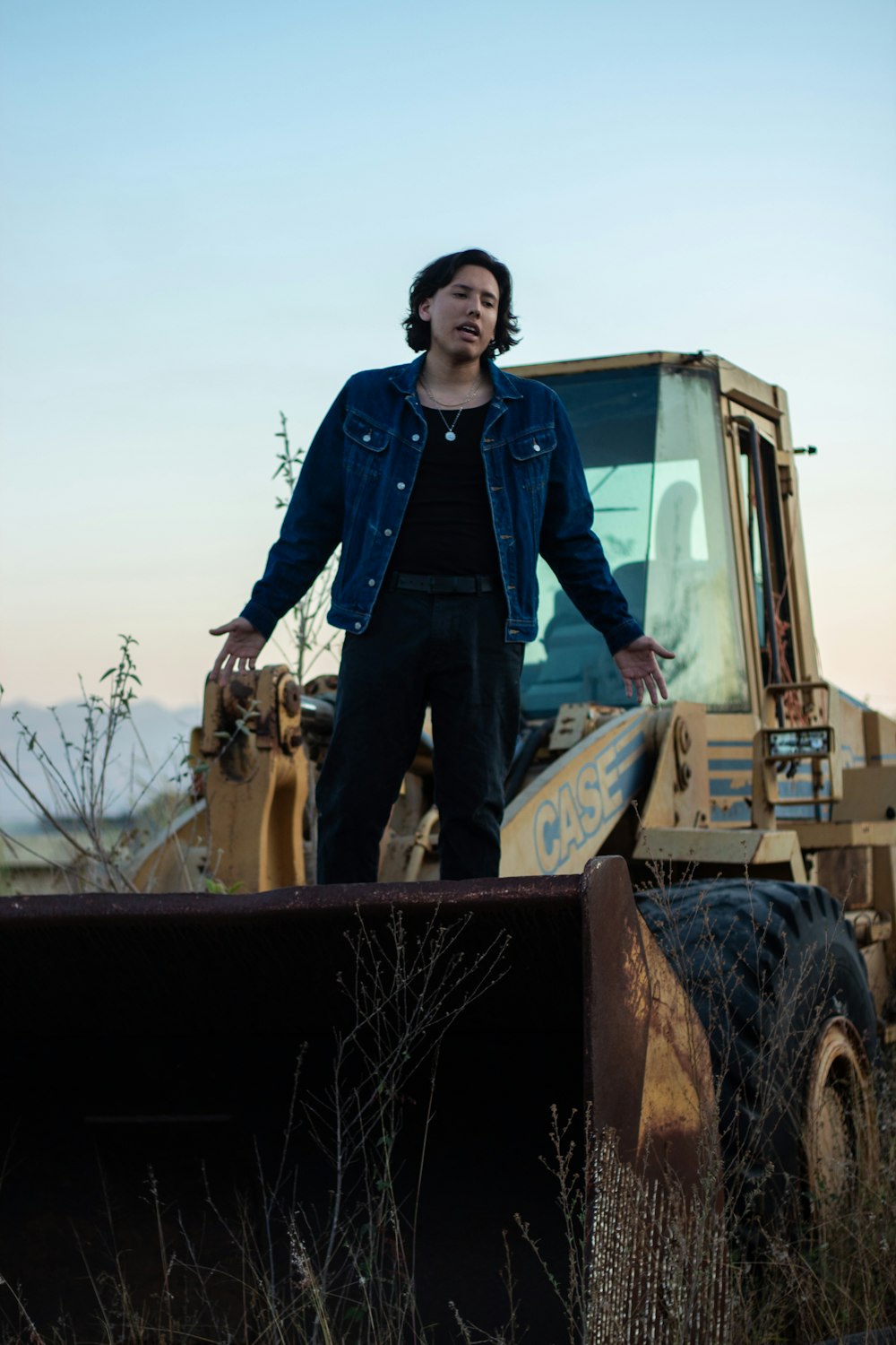 a man standing next to a bulldozer in a field