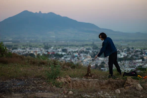 Professional detector operator using a gold detector near a rugged mountain landscape at dawn