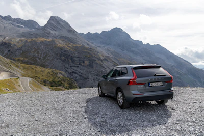 A traveler checking their map beside a rental car parked near a mountain trail.