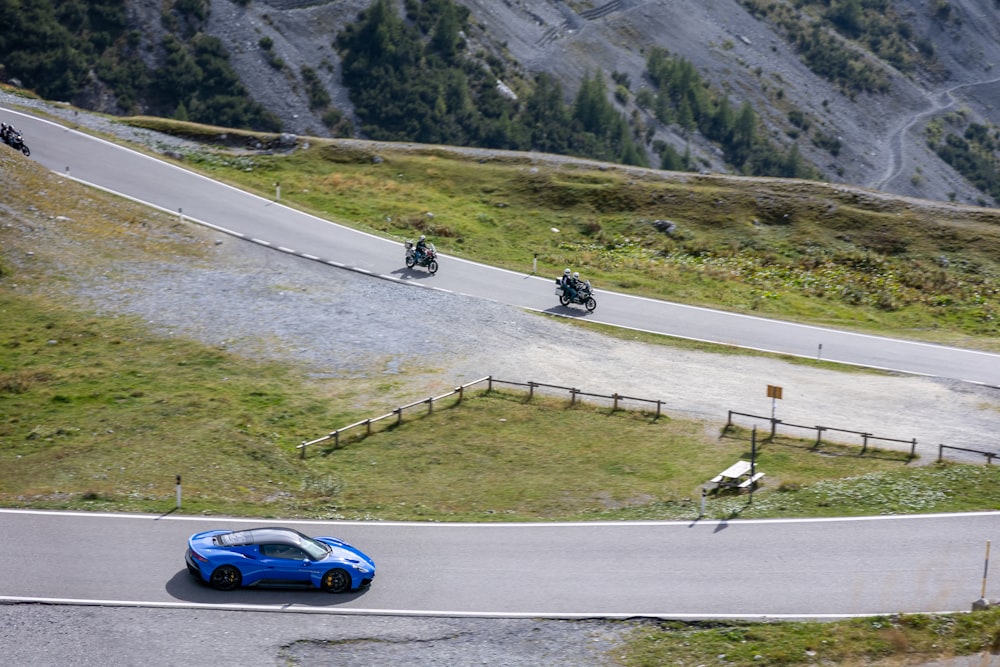 a blue car driving down a winding road