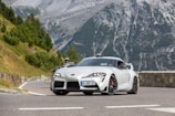 A sporty coupe cruising along a scenic highway with desert mountains in view.