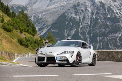 A sporty coupe cruising along a scenic highway with desert mountains in view.