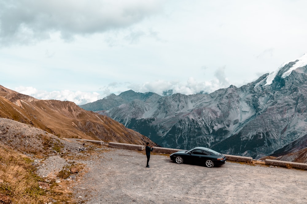 a person standing next to a car on a road