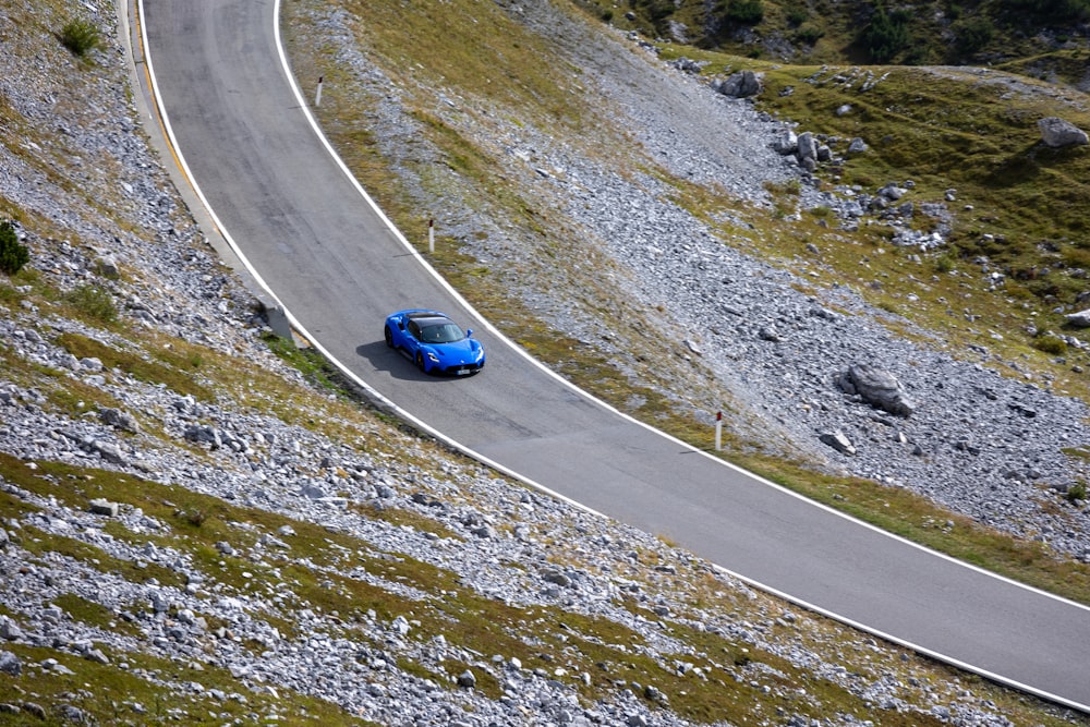 a blue car driving down a winding road