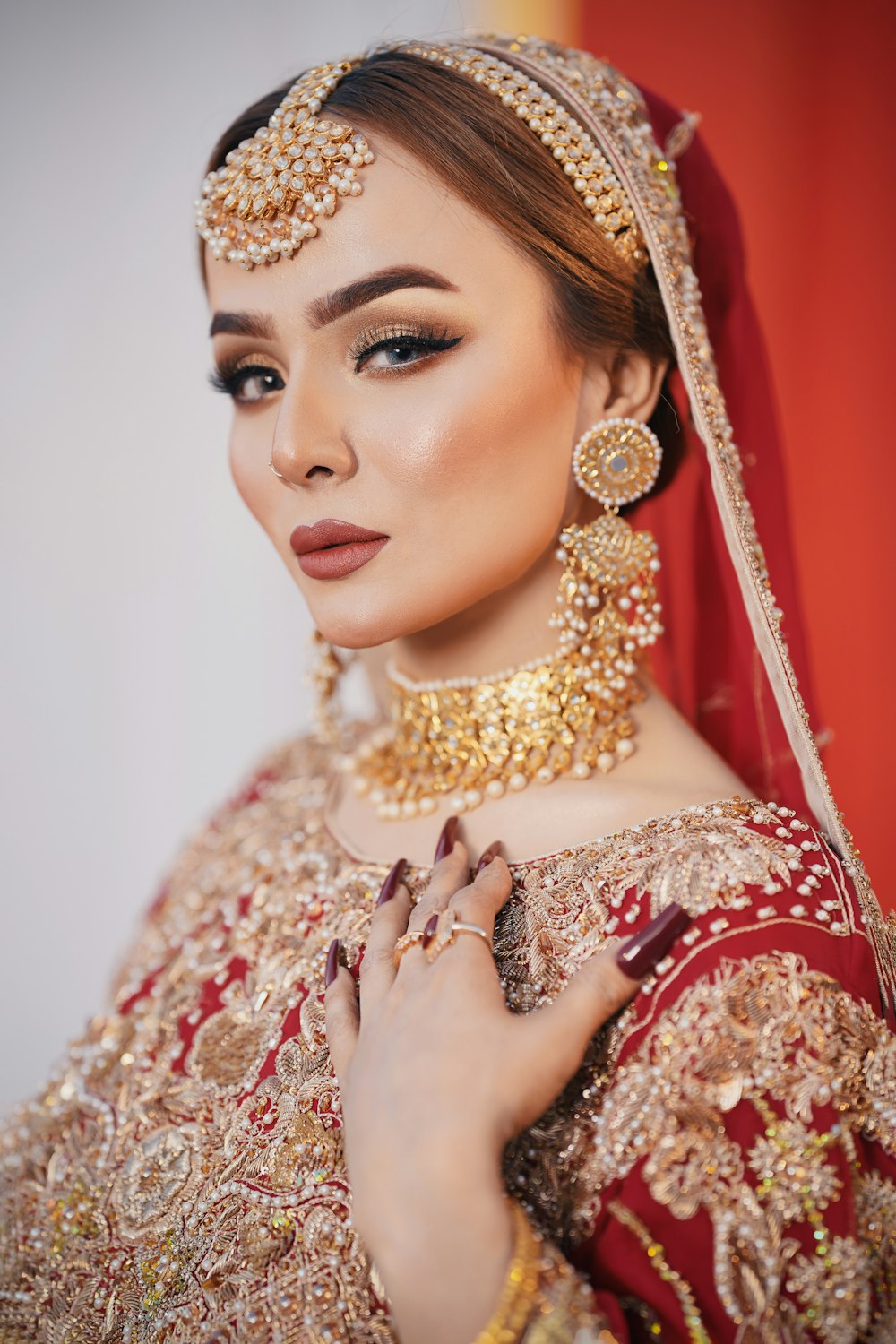 a woman wearing a red and gold bridal outfit