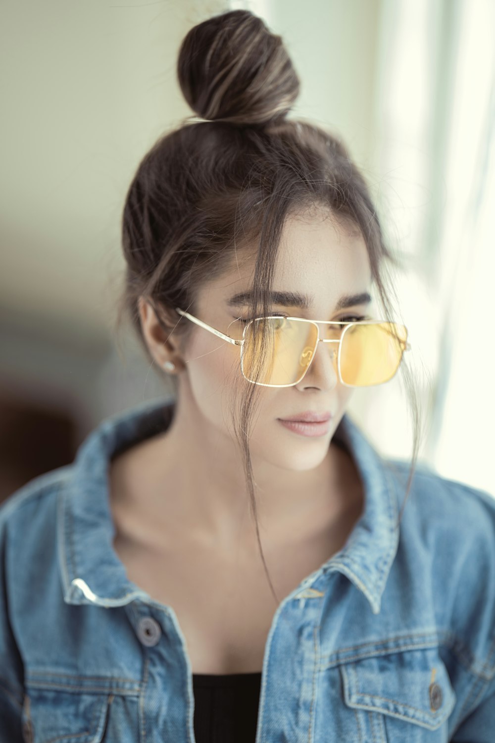 a woman wearing a denim jacket and yellow sunglasses