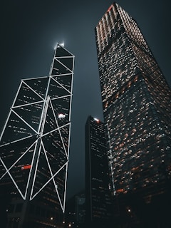 two skyscrapers lit up at night in a city