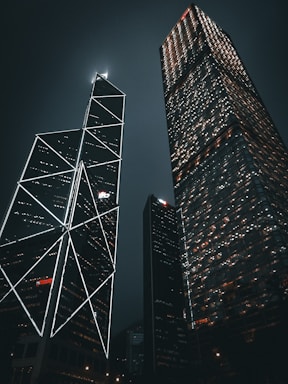 two skyscrapers lit up at night in a city