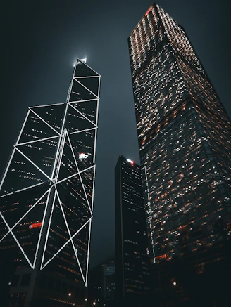 two skyscrapers lit up at night in a city