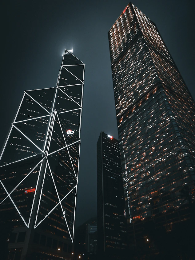 two skyscrapers lit up at night in a city