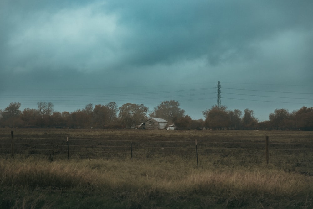 a field with a fence and a house in the distance