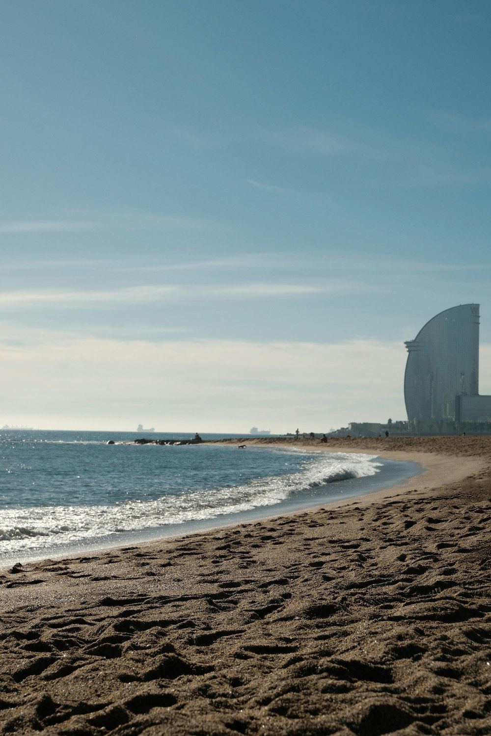 a sandy beach next to the ocean under a blue sky