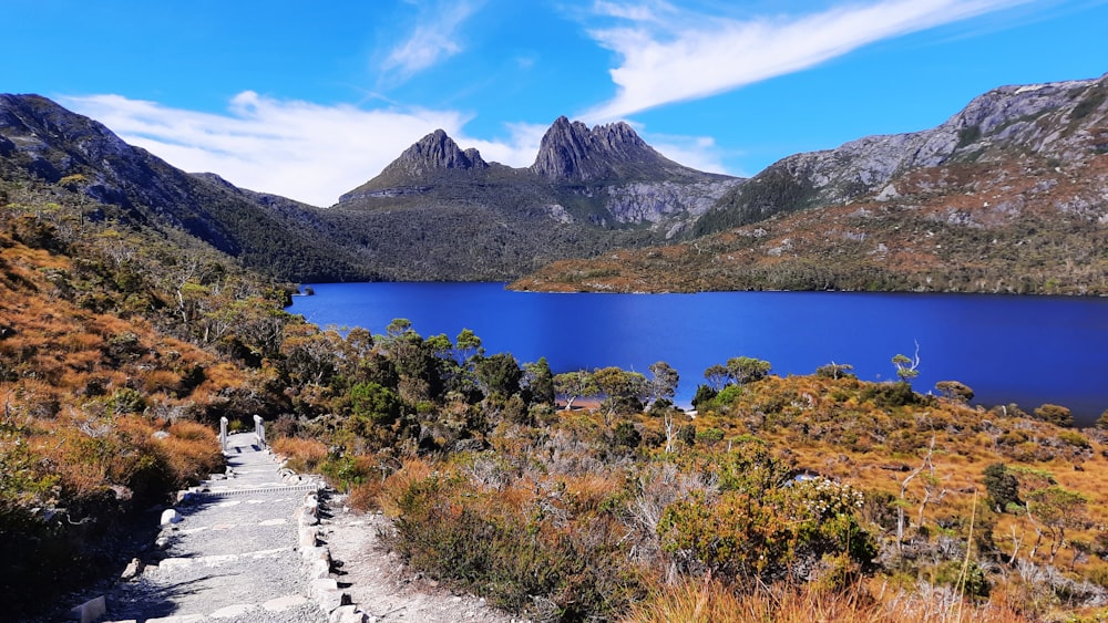 a path leading to a lake surrounded by mountains