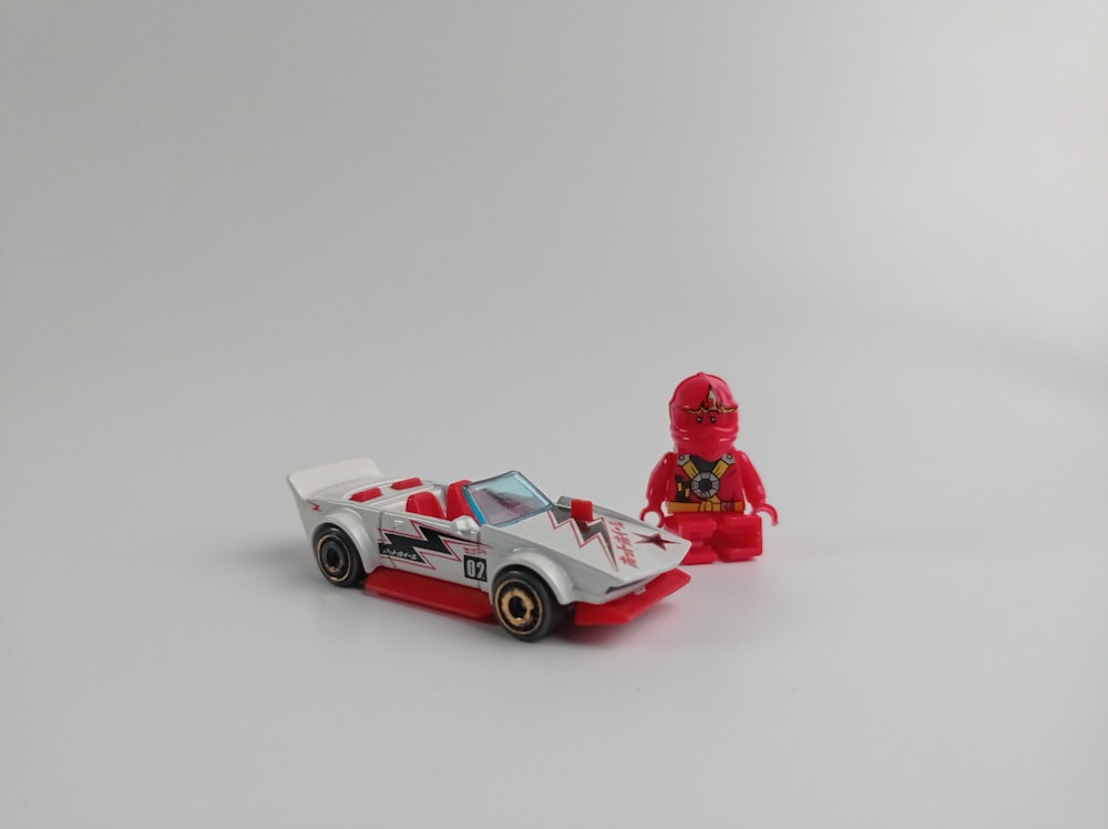 a lego figure sitting next to a toy car