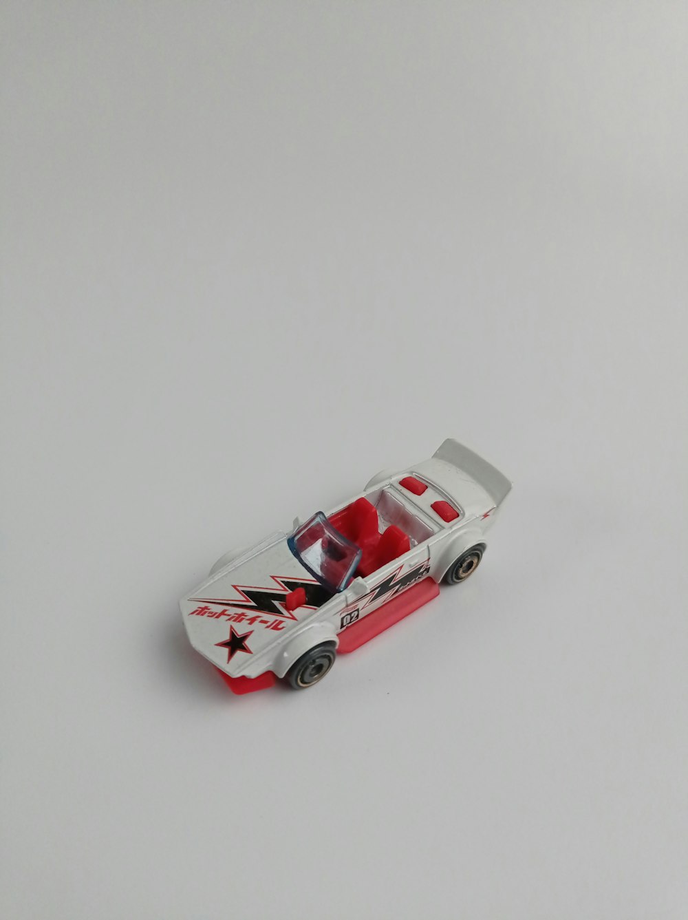 a red and white toy car on a white surface
