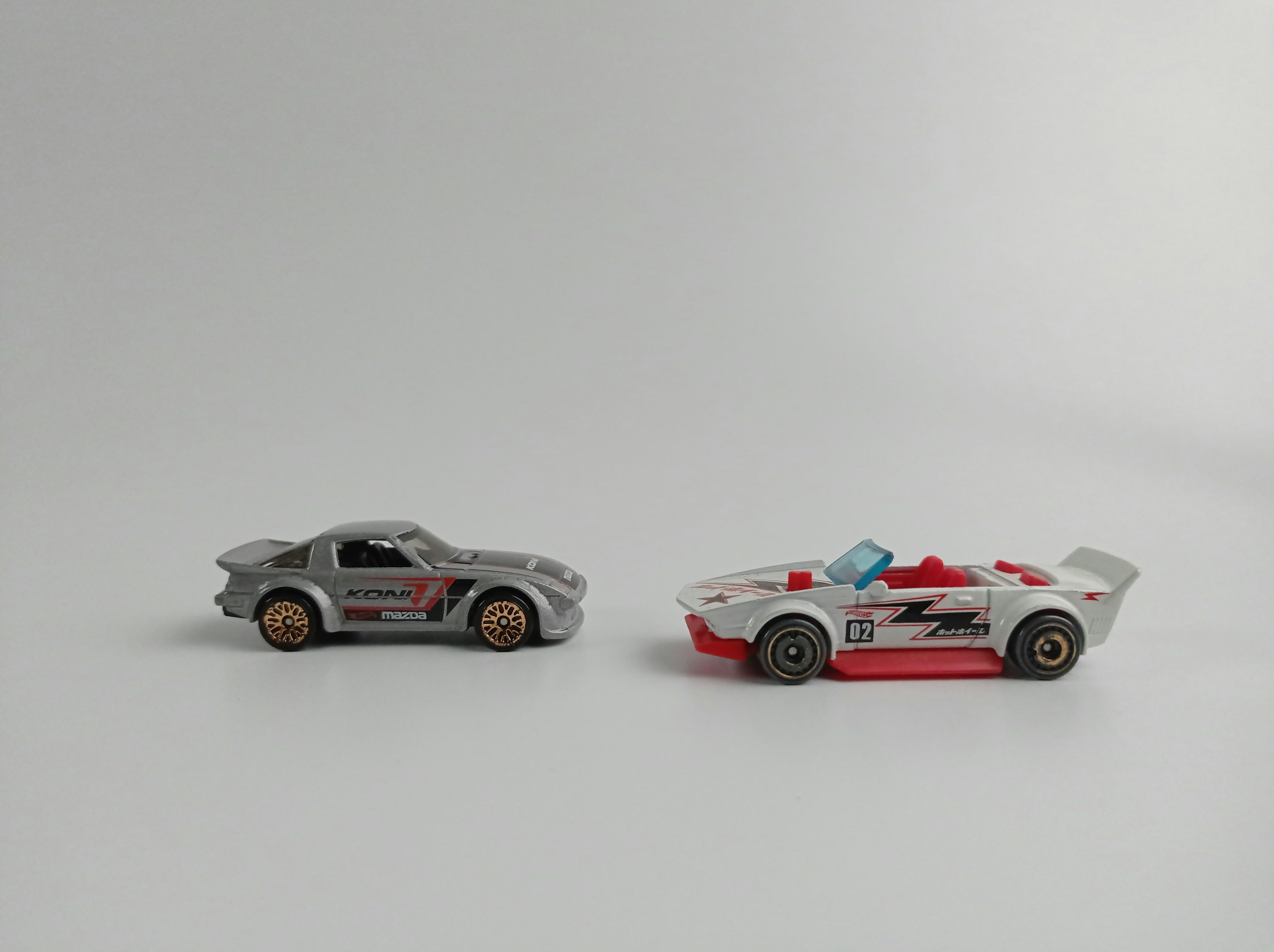 two toy cars sitting side by side on a white surface