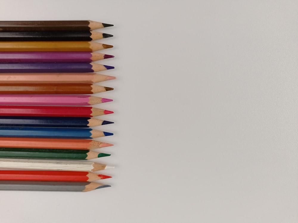 a group of colored pencils lined up on a white surface