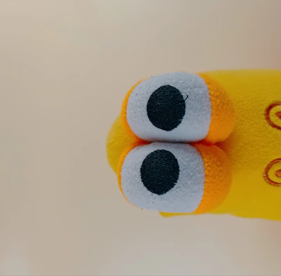 Whimsical stuffed animal with stitched details and button eyes.