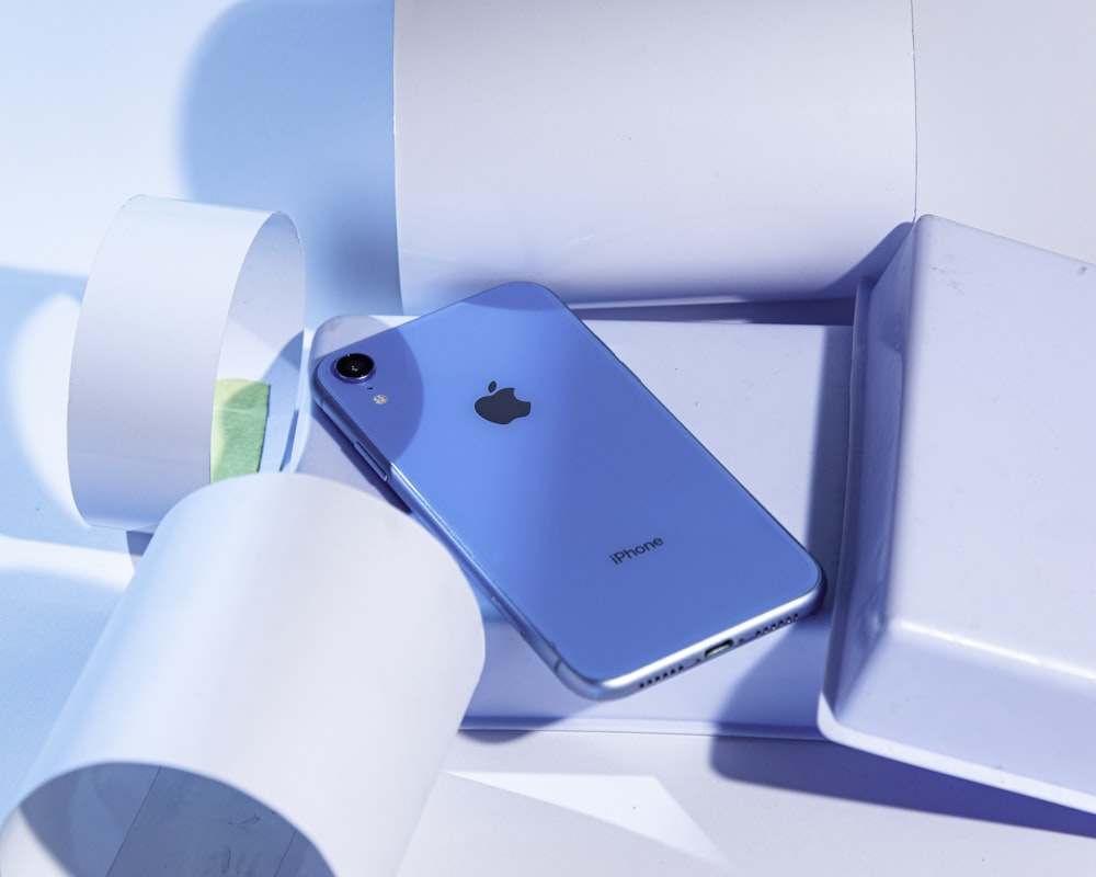 a blue iphone sitting in a box next to a roll of toilet paper