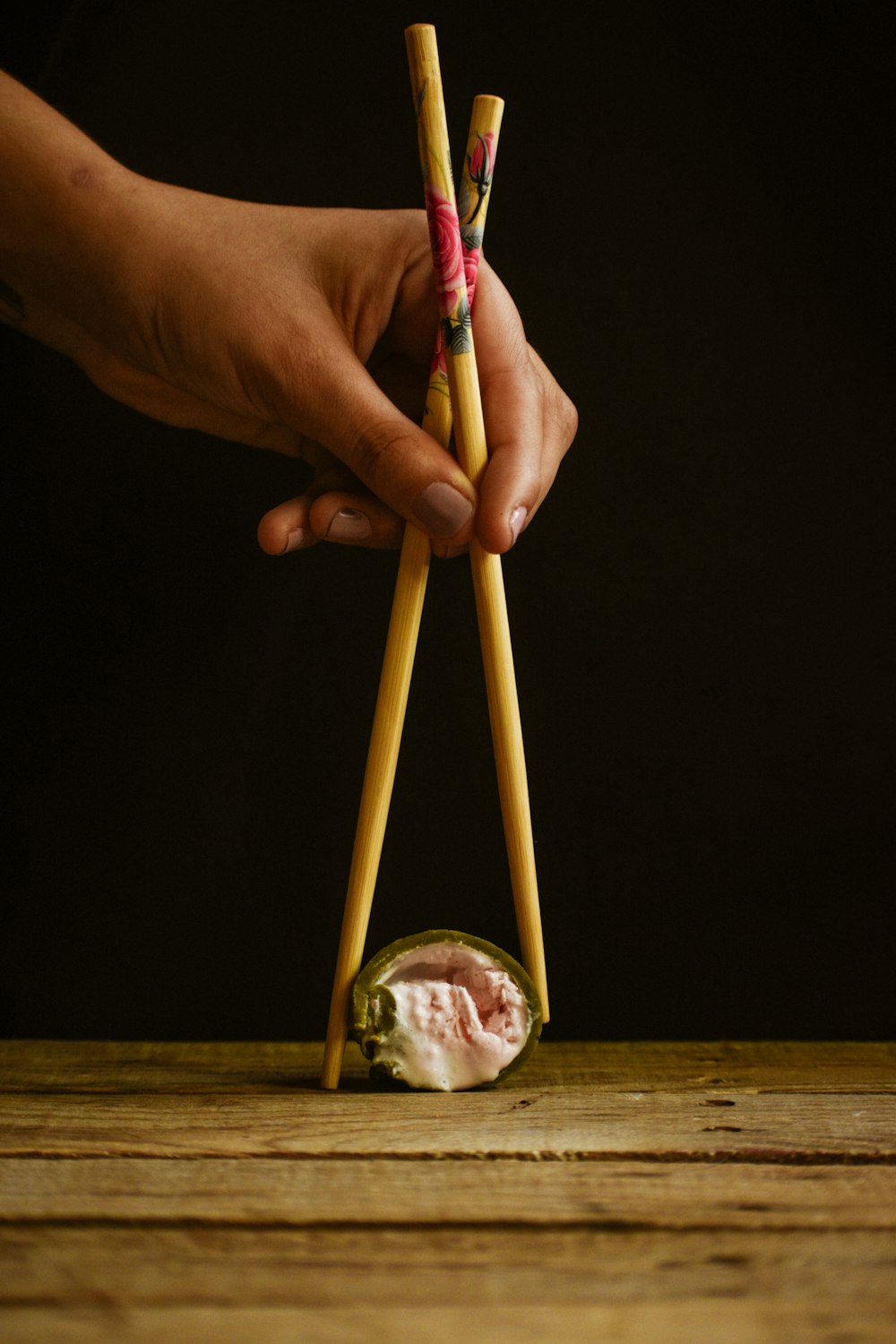 a person holding two chopsticks over a sushi