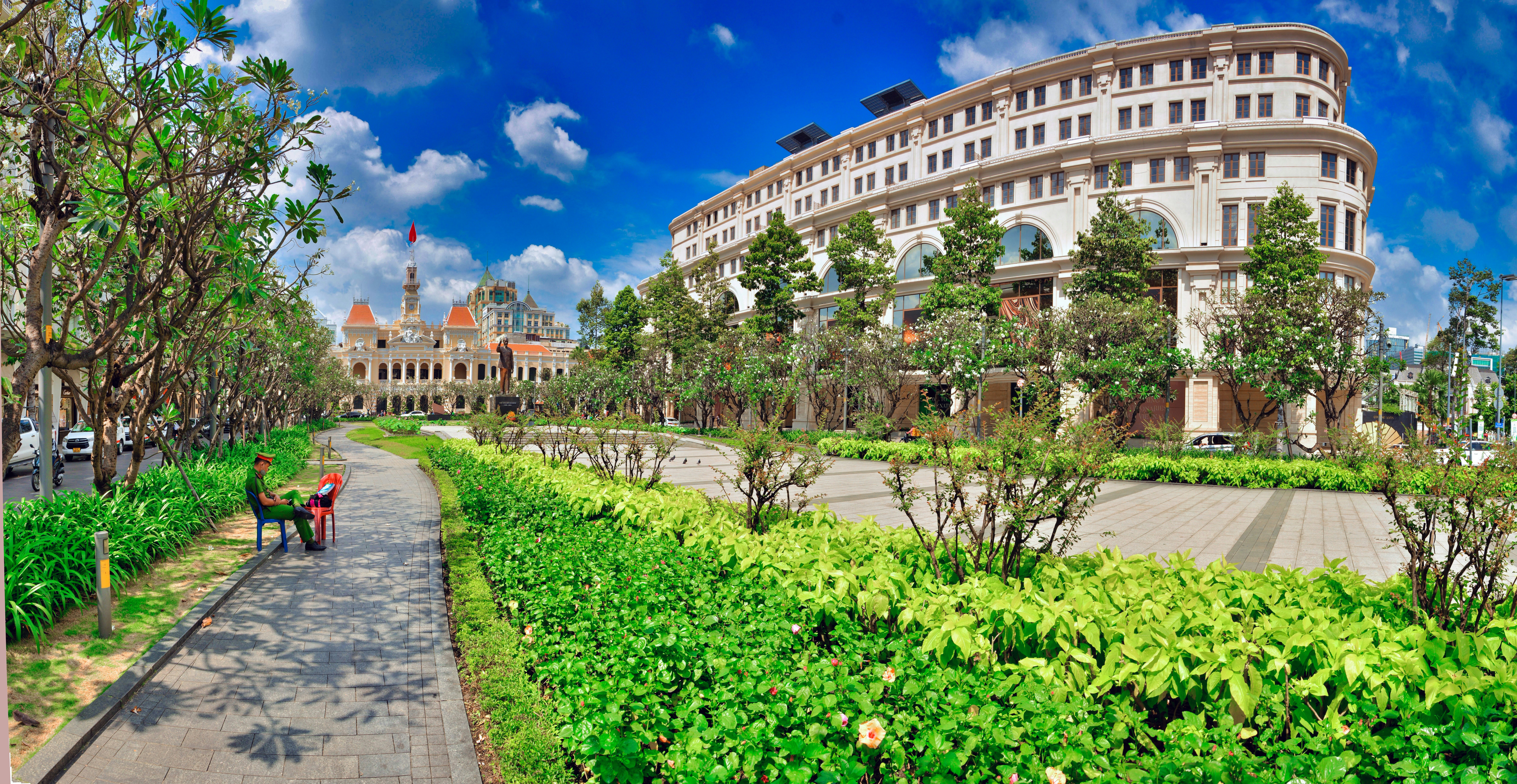 A man walking down a sidewalk next to a lush green park photo – Free ...
