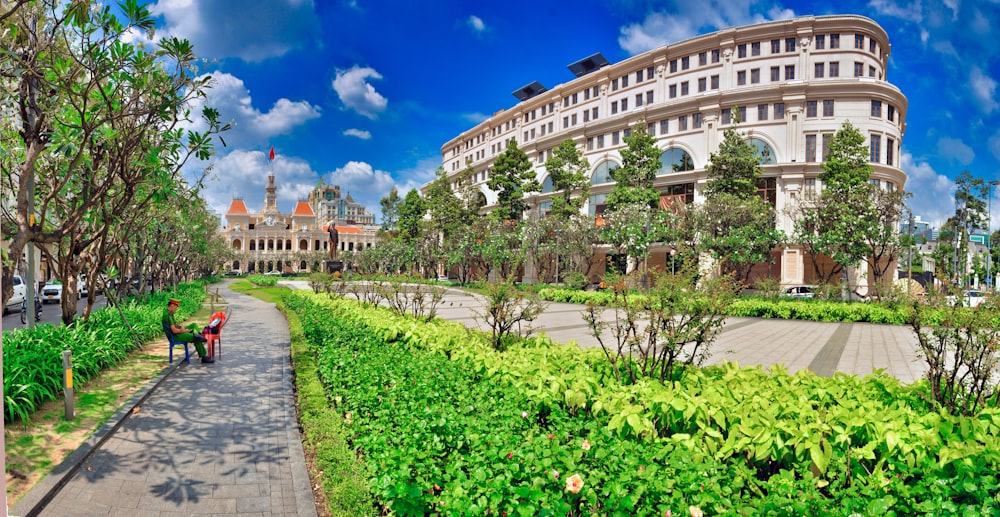 a man walking down a sidewalk next to a lush green park