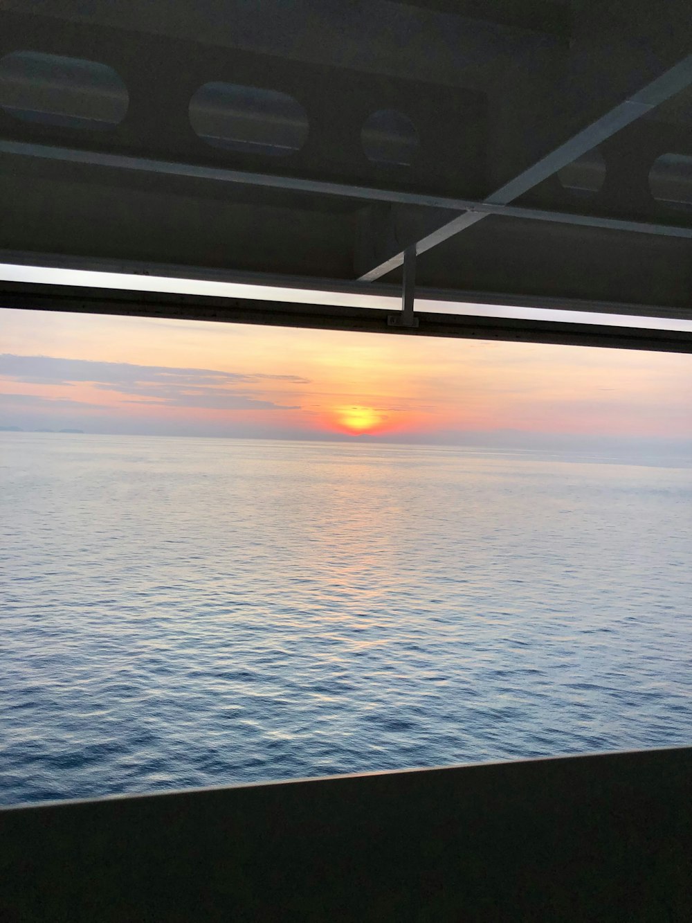 the sun is setting over the ocean from a boat
